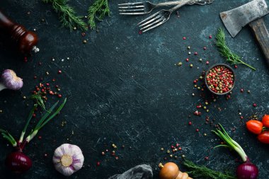 Siyah mutfak afişi: Siyah taşlı arka planda sebze ve baharatlar. Üst görünüm.