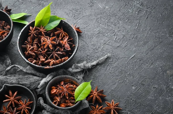 Anise stars in bowls on black stone background. Badian - Indian spices. Top view.