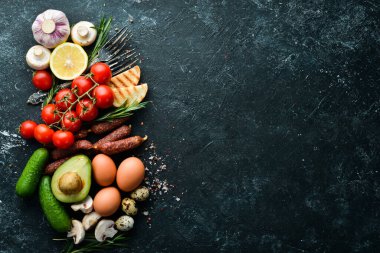 Sağlıklı yiyecekler: domates, makarna, baharat, sebze ve sosis. Üst Manzara. Siyah taş arkaplan.