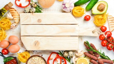 Yemek arkaplanı. Beyaz ahşap arka planda kuru makarna, domates, baharat ve sebzeler. Üst görünüm.
