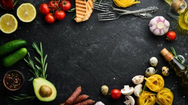 Tagliatelle makarna ve malzeme pişirme geçmişi. İtalyan mutfağının siyah taş arka planı. Üst görünüm.