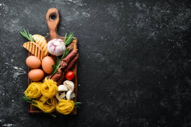 Tagliatelle makarna ve malzeme pişirme geçmişi. İtalyan mutfağının siyah taş arka planı. Üst görünüm.