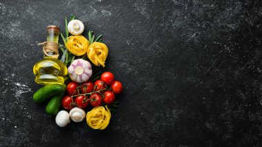 Tagliatelle makarna ve malzeme pişirme geçmişi. İtalyan mutfağının siyah taş arka planı. Üst görünüm.