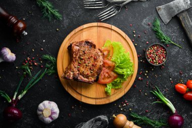 Kemiğin üzerinde biftek ve tahtada sebze. Barbekü menüsü. Üst görünüm.