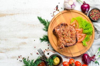 Kemiğin üzerinde biftek ve tahtada sebze. Barbekü menüsü. Üst görünüm.