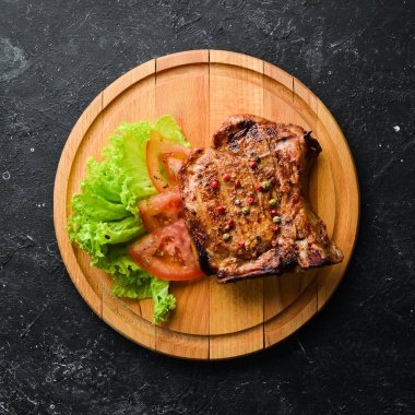 Kemiğin üzerinde biftek ve tahtada sebze. Barbekü menüsü. Üst görünüm.