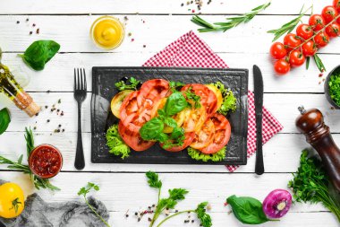 Siyah taş tabakta taze domates ve fesleğen salatası. Üst Manzara. Boş kopyalama alanı.