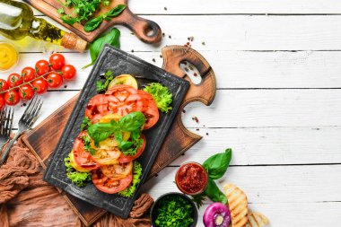 Siyah taş tabakta taze domates ve fesleğen salatası. Üst Manzara. Boş kopyalama alanı.