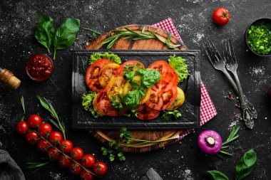 Siyah taş tabakta taze domates ve fesleğen salatası. Üst Manzara. Boş kopyalama alanı.