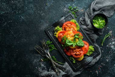 Siyah taş tabakta taze domates ve fesleğen salatası. Üst Manzara. Boş kopyalama alanı.