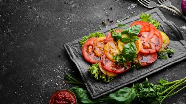 Siyah taş tabakta taze domates ve fesleğen salatası. Üst Manzara. Boş kopyalama alanı.