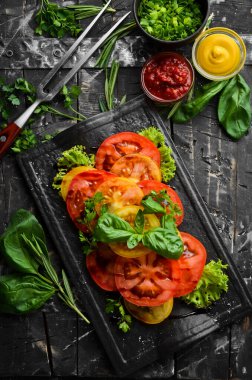 Siyah taş tabakta taze domates ve fesleğen salatası. Üst Manzara. Boş kopyalama alanı.