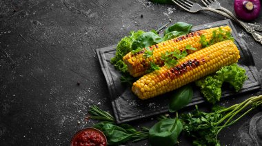 Fırında mısır, baharat ve tuzlu siyah taş tabakta. Üst Manzara. Boş kopyalama alanı.