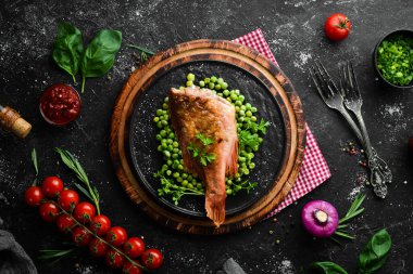 Siyah taş tabakta yeşil bezelyeli kırmızı deniz levreği. Üst Manzara. Boş kopyalama alanı.