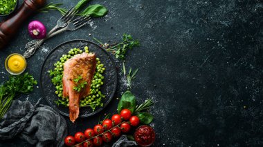 Siyah taş tabakta yeşil bezelyeli kırmızı deniz levreği. Üst Manzara. Boş kopyalama alanı.