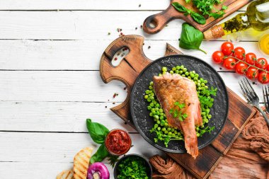 Siyah taş tabakta yeşil bezelyeli kırmızı deniz levreği. Üst Manzara. Boş kopyalama alanı.