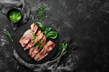 Siyah taş tabakta fesleğenli kızarmış pastırma dilimleri. Üst Manzara. Boş kopyalama alanı.