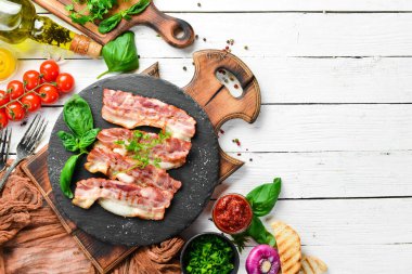 Siyah taş tabakta fesleğenli kızarmış pastırma dilimleri. Üst Manzara. Boş kopyalama alanı.