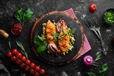 Siyah taş tabakta pilav ve sebzeli kalamar. Deniz ürünleri. Üst Manzara. Boş kopyalama alanı.