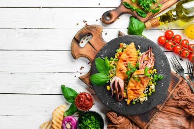 Siyah taş tabakta pilav ve sebzeli kalamar. Deniz ürünleri. Üst Manzara. Boş kopyalama alanı.