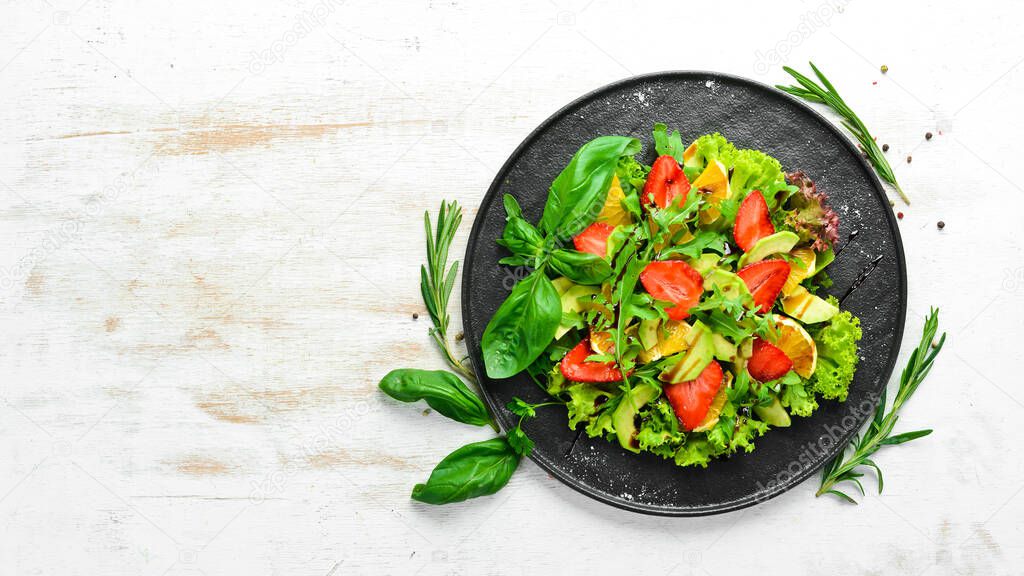Healthy food: salad of arugula, avocado, strawberry and orange. Top view. Free space for your text.