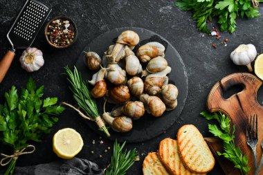 Siyah taş tabakta maydanozlu Taze Üzüm Salyangozu. Üst görünüm.