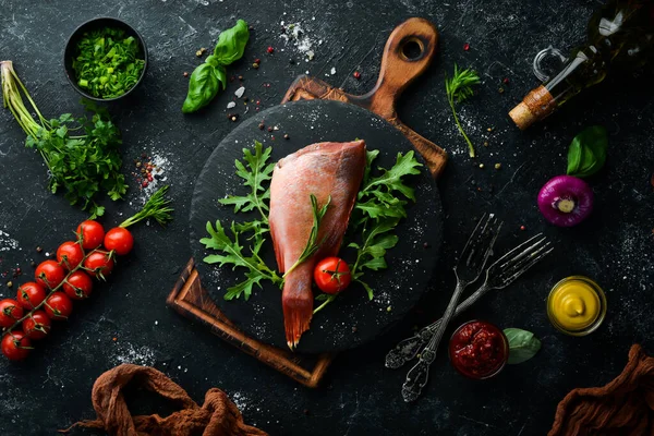 Çiğ deniz kırmızı levreği, biberiye ve siyah tabakta baharatlar. Deniz ürünleri. Üst Manzara. Metnin için boş yer.