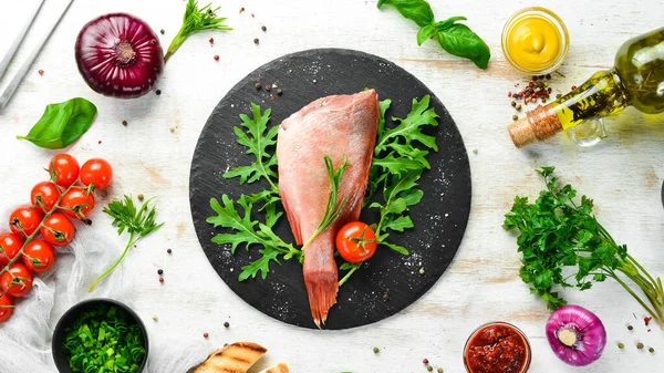 Çiğ deniz kırmızı levreği, biberiye ve siyah tabakta baharatlar. Deniz ürünleri. Üst Manzara. Metnin için boş yer.