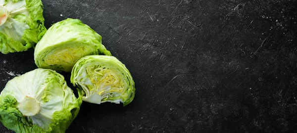 Iceberg lettuce. Fresh lettuce on a black stone background. Top view. Free copy space.