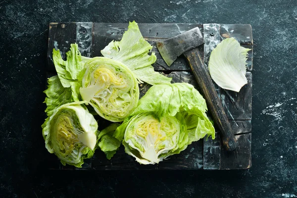 Iceberg lettuce. Fresh lettuce on a black stone background. Top view. Free copy space.