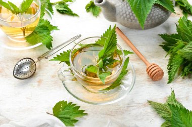 Beyaz arka planda fincanlarda ısırgan otu çayı. Bitkisel sağlıklı içecekler. Üst Manzara. Metnin için boş yer.