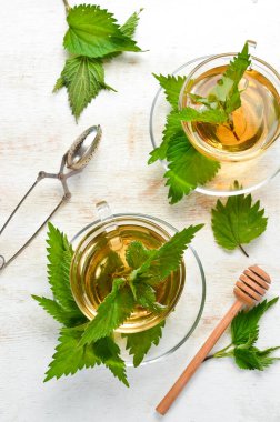 Beyaz arka planda fincanlarda ısırgan otu çayı. Bitkisel sağlıklı içecekler. Üst Manzara. Metnin için boş yer.