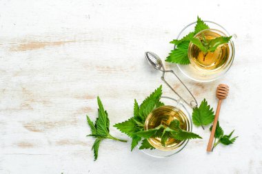 Beyaz arka planda fincanlarda ısırgan otu çayı. Bitkisel sağlıklı içecekler. Üst Manzara. Metnin için boş yer.