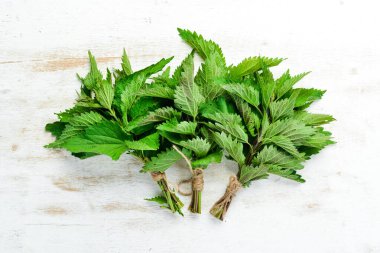 Beyaz ahşap arka planda taze yeşil ısırgan otları. Sağlıklı bitkiler. Üst görünüm.