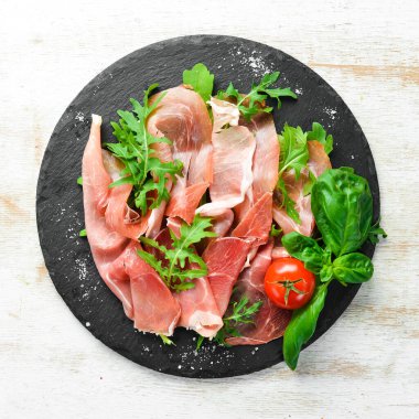 Siyah tabakta roka ve fesleğenli Prosciutto. İspanyol mutfağı. Üst Manzara. Metnin için boş yer.