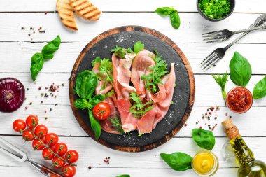 Siyah tabakta roka ve fesleğenli Prosciutto. İspanyol mutfağı. Üst Manzara. Metnin için boş yer.