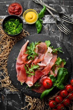 Siyah tabakta roka ve fesleğenli Prosciutto. İspanyol mutfağı. Üst Manzara. Metnin için boş yer.