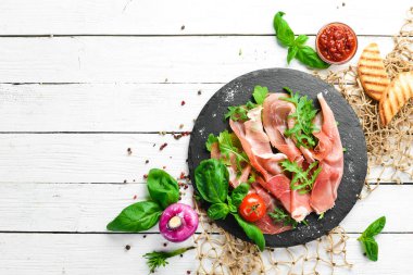 Siyah tabakta roka ve fesleğenli Prosciutto. İspanyol mutfağı. Üst Manzara. Metnin için boş yer.