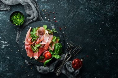 Siyah tabakta roka ve fesleğenli Prosciutto. İspanyol mutfağı. Üst Manzara. Metnin için boş yer.