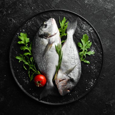 Maydanozlu çiğ Dorado balığı ve siyah tabakta baharat. Üst Manzara. Metnin için boş yer.