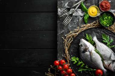 Maydanozlu çiğ Dorado balığı ve siyah tabakta baharat. Üst Manzara. Metnin için boş yer.