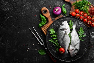 Maydanozlu çiğ Dorado balığı ve siyah tabakta baharat. Üst Manzara. Metnin için boş yer.
