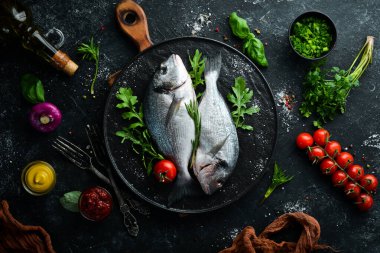 Maydanozlu çiğ Dorado balığı ve siyah tabakta baharat. Üst Manzara. Metnin için boş yer.
