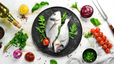 Maydanozlu çiğ Dorado balığı ve siyah tabakta baharat. Üst Manzara. Metnin için boş yer.