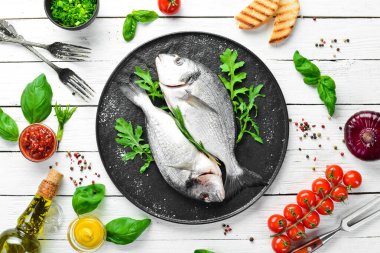 Maydanozlu çiğ Dorado balığı ve siyah tabakta baharat. Üst Manzara. Metnin için boş yer.