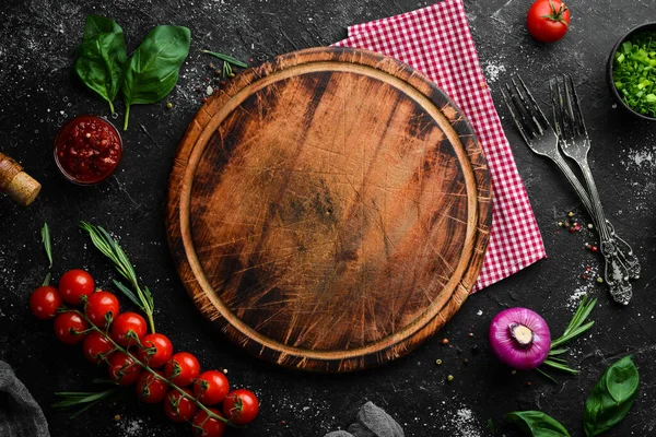 Yemek arkaplanı. Mutfak tahtası, sebzeler, baharatlar ve mutfak gereçleri eski masada. Boş kopyalama alanı.