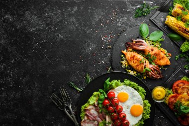 Yemek arkaplanı. Siyah taş arka planda balık, et ve sebze seti. Üst Manzara. Boş kopyalama alanı.