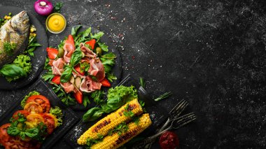 Yemek arkaplanı. Siyah taş arka planda balık, et ve sebze seti. Üst Manzara. Boş kopyalama alanı.