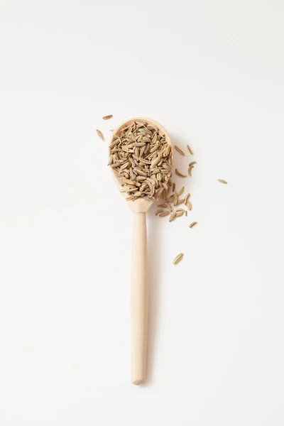 Fennel fruits in a wooden spoon on a white — Stock Photo, Image