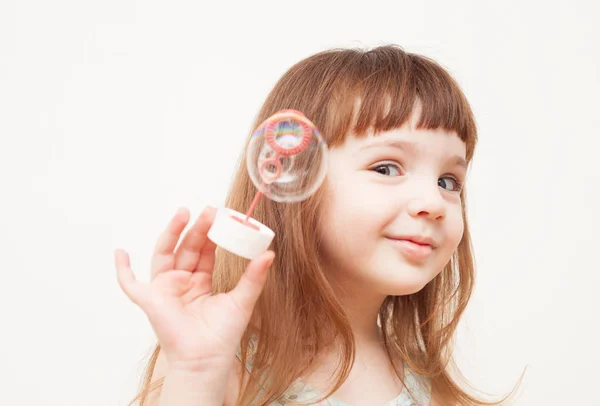 Девушка дует мыльные пузыри на монофоническом фоне — стоковое фото